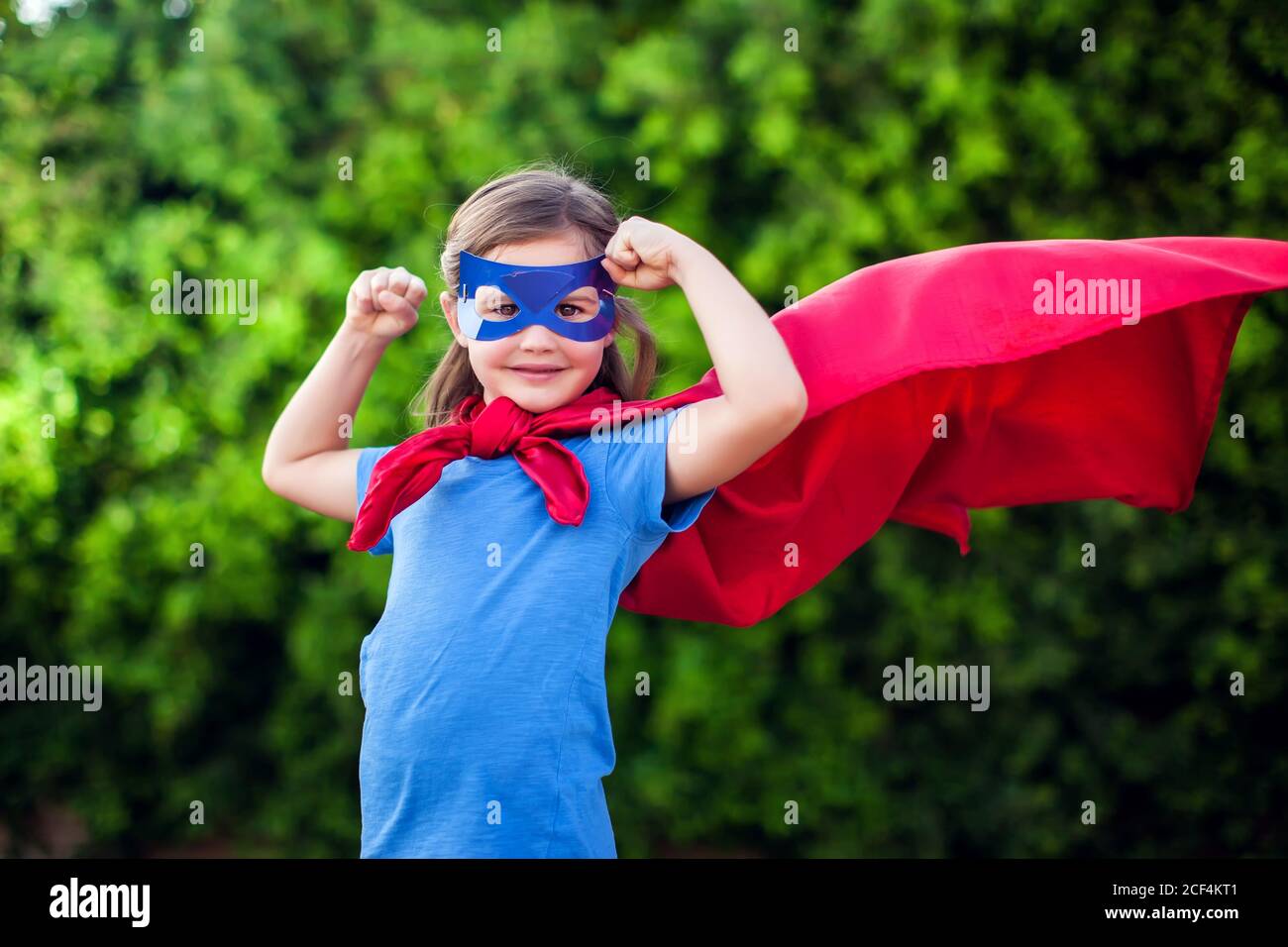 Super-héros petite fille sur fond vert en extérieur. Enfance, succès et concept de puissance Banque D'Images