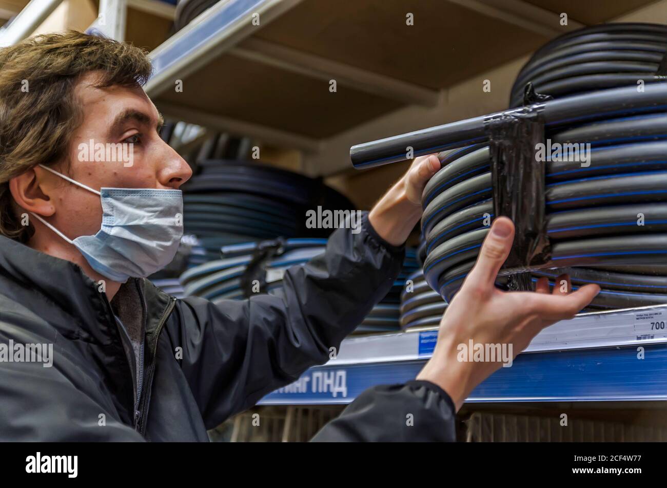 Homme dans le masque de choix de tuyau d'eau debout près de la présentation en magasin Banque D'Images