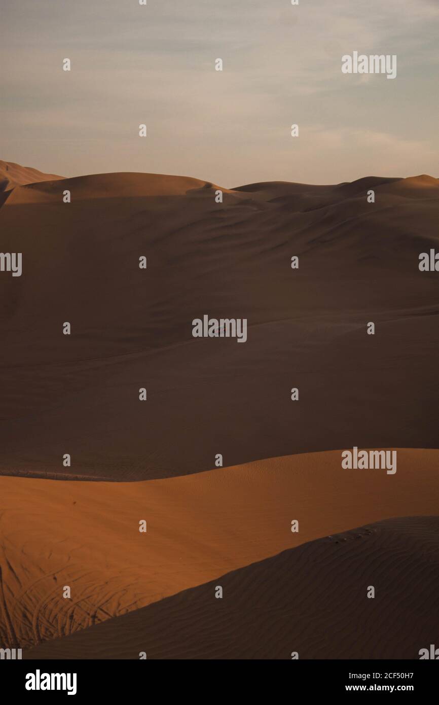 Vue pittoresque sur les dunes de sable sec avec la route solitaire et Voiture dans le désert du Pérou ensoleillé en soirée Banque D'Images