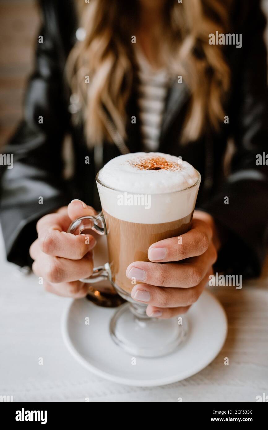 Courte inreconnaissable tendance belle femme blonde boire d'un verre de délicieux café mousseux Banque D'Images