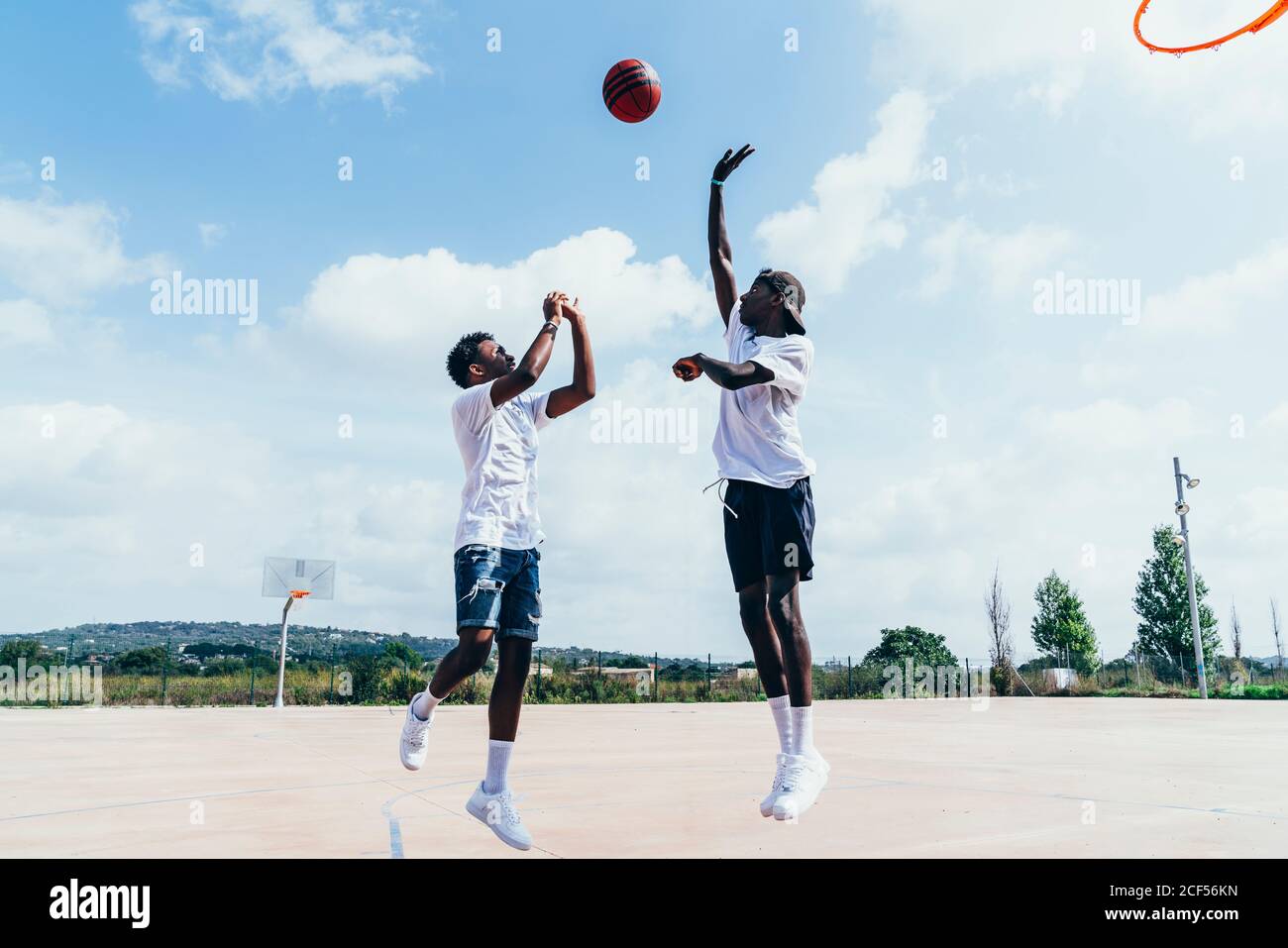 Vue latérale des Afro-américains jouant au basket-ball dans Bright journée sur le terrain de jeu Banque D'Images