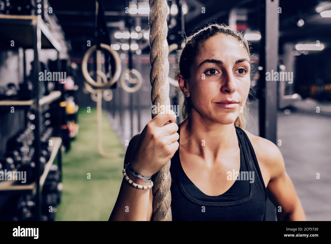 Femme musclée avec corde et regardant la manière sur la salle de gym Banque D'Images