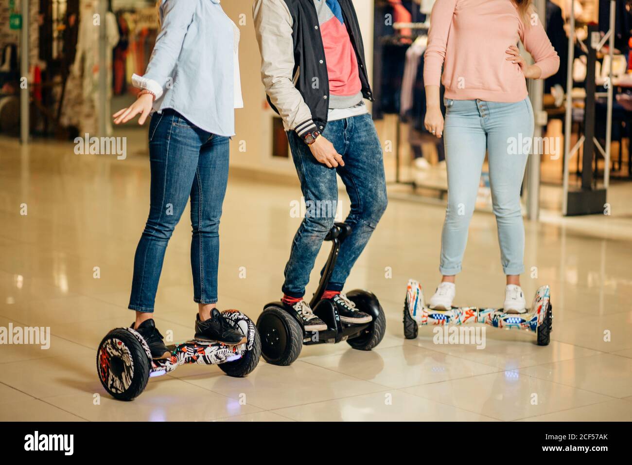 Un jeune homme et deux femmes à monter sur le Hoverboard dans le centre  commercial. Technologies de contenu. Un nouveau mouvement. Gros plan du  Skatebo électrique à équilibrage automatique à deux roues