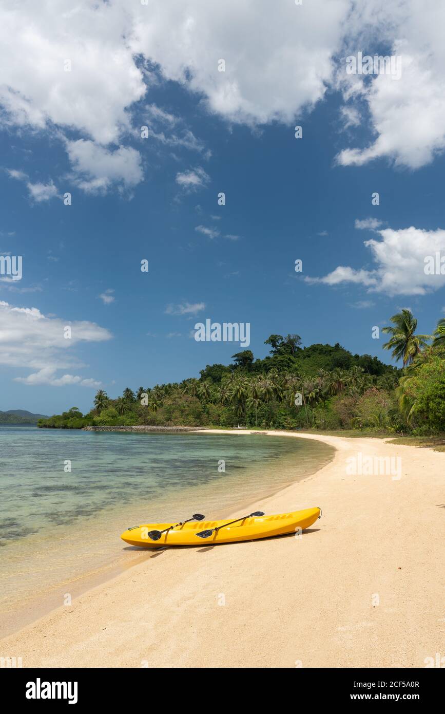 Canot jaune vide sur la plage de sable de l'île tropicale arrière-plan de la jungle et du ciel bleu Banque D'Images