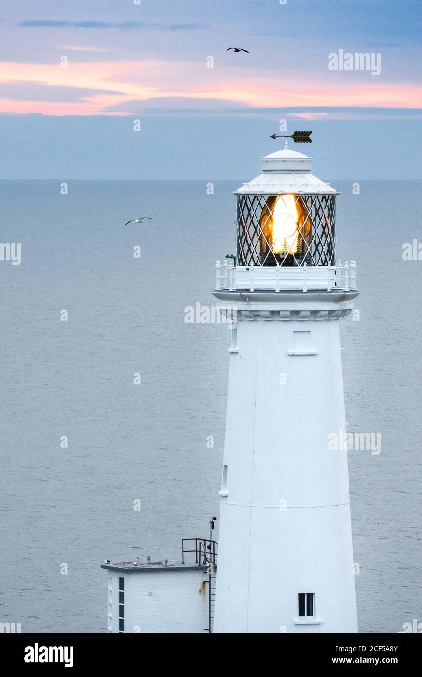 Phare blanc avec lampe d'éclairage et flèche sur le toit à Coucher de  soleil dans la mer sereine au pays de Galles Photo Stock - Alamy