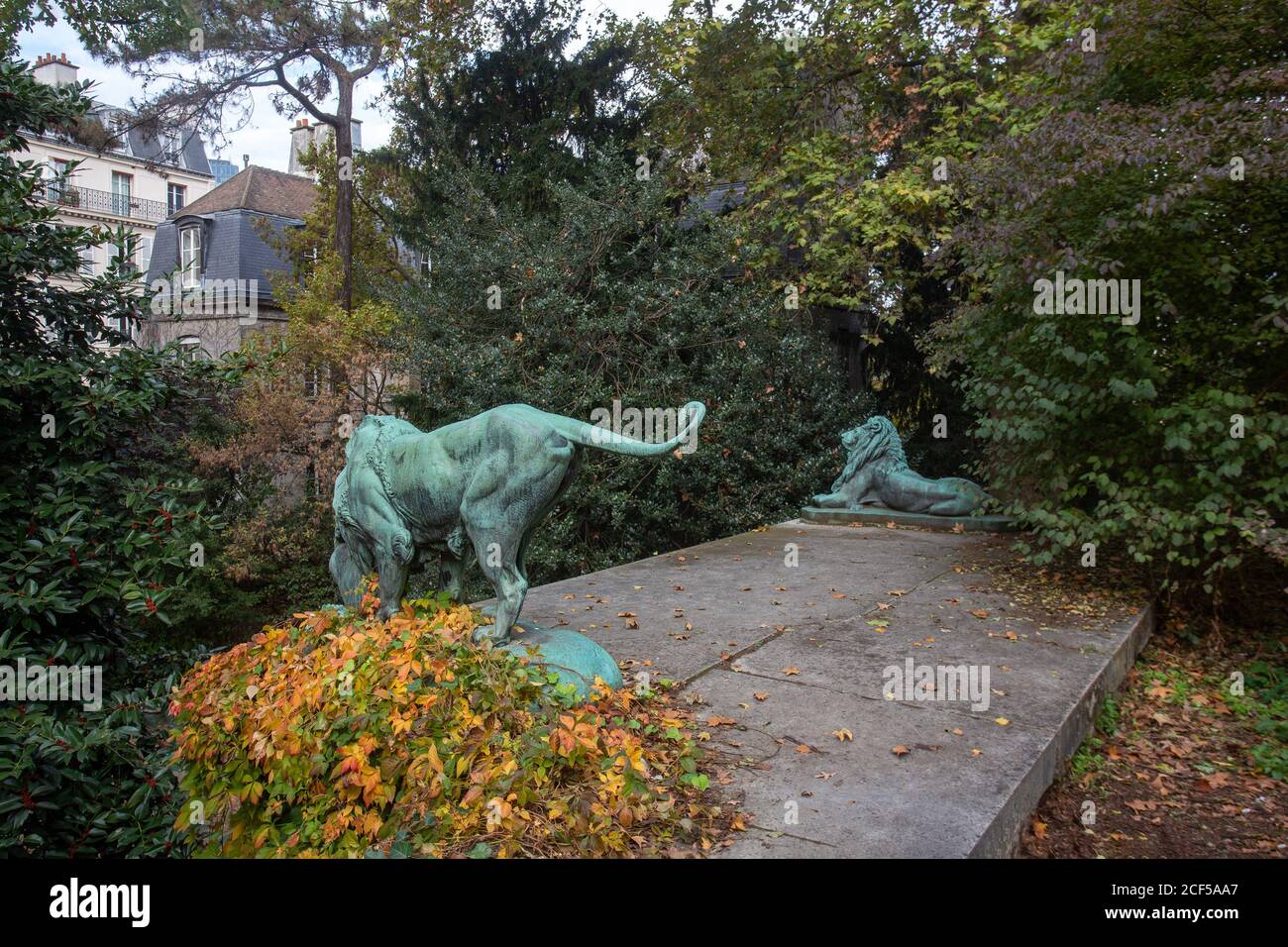 Sculptures de lions dans le jardin des plantes de Paris. Feuilles d'automne jaune et orange sur terre Banque D'Images