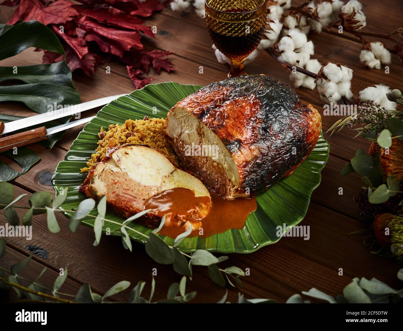 Du dessus de poulet cuit au four délicieux farci avec du jambon et des noix  et servi sur une table de bois au milieu de brindilles de plantes près du  verre de