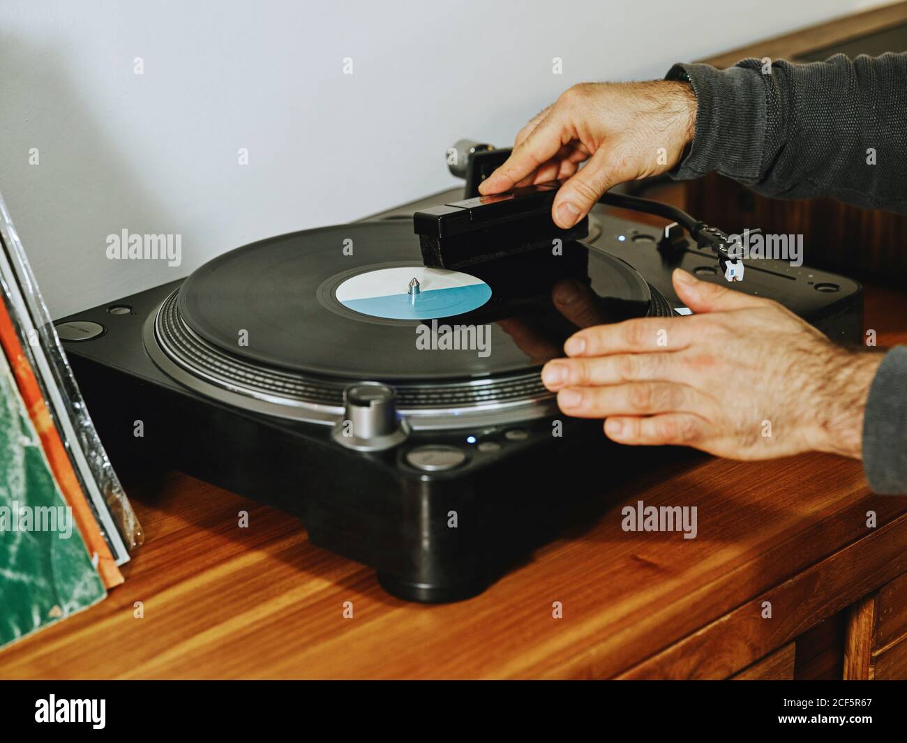 Rognée personne non reconnaissable fixant la table tournante et appréciant des chansons sur le rétro disque en vinyle tout en se refroidissant à la maison Banque D'Images
