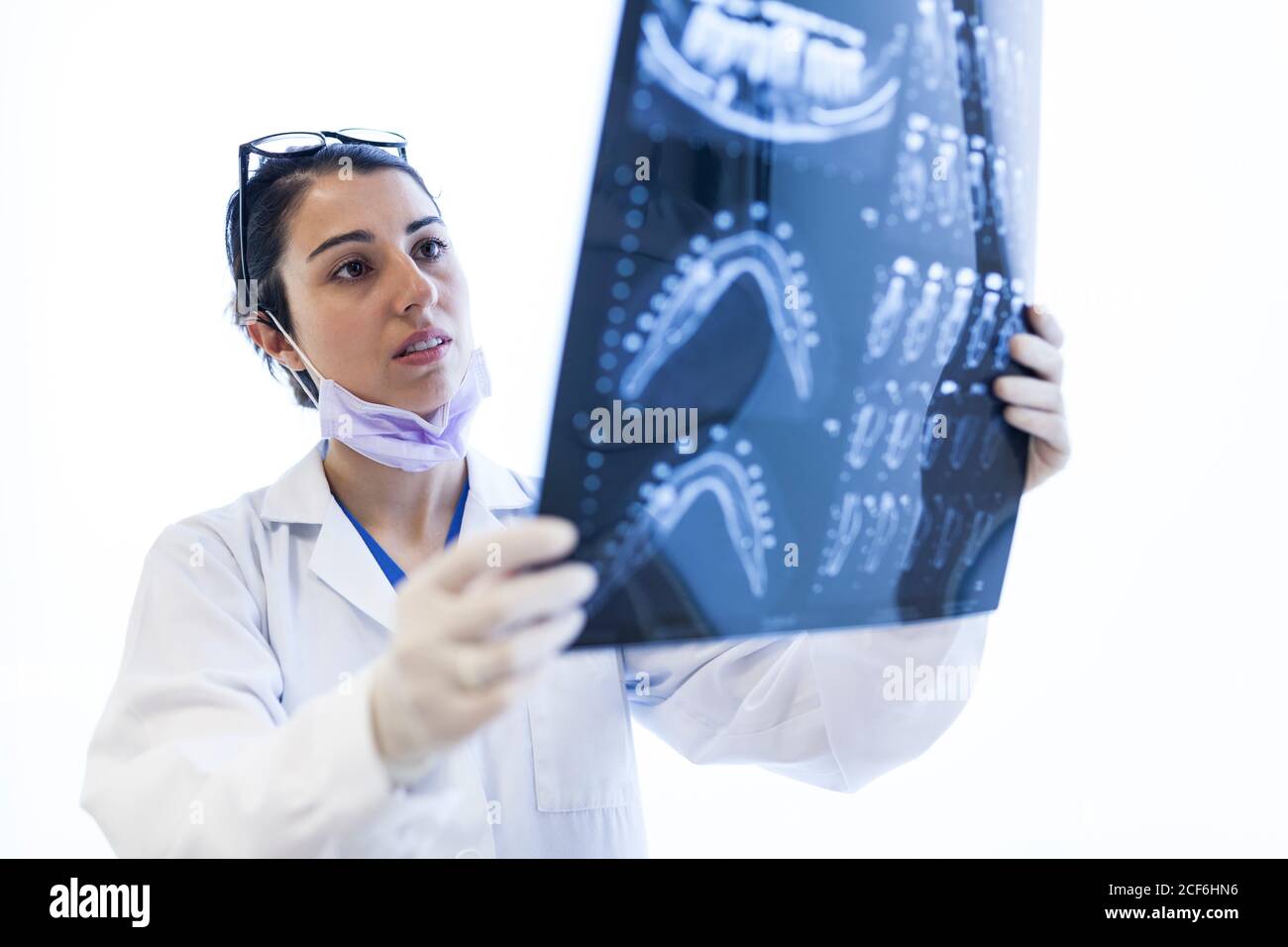Jeune belle femme dentiste en robe médicale, gants, masque et lunettes de contrôle x-ray isolé sur fond blanc Banque D'Images
