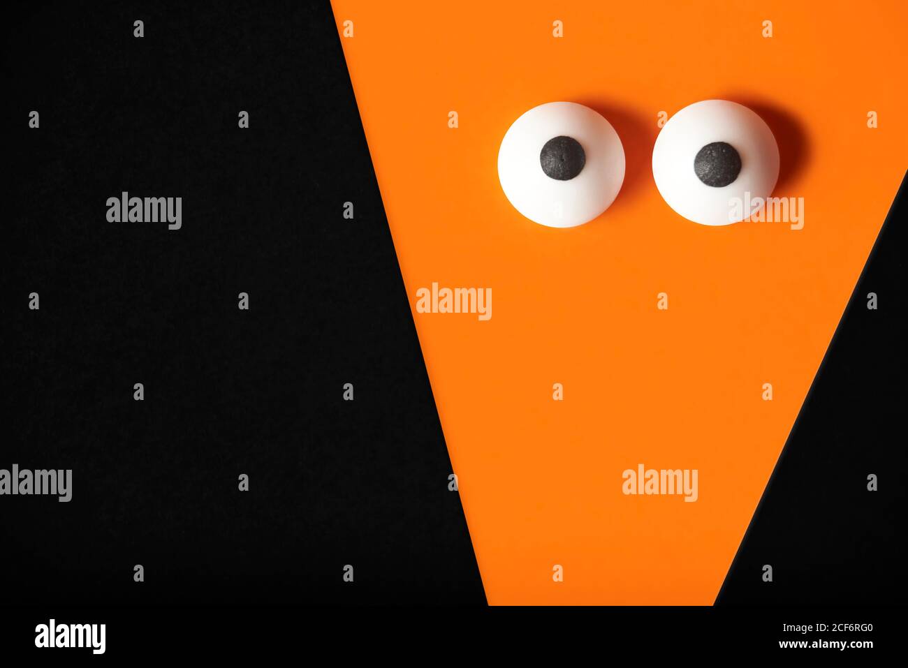 Arrière-plan Halloween, fantôme orange avec yeux renflés sur noir, espace de copie. Banque D'Images