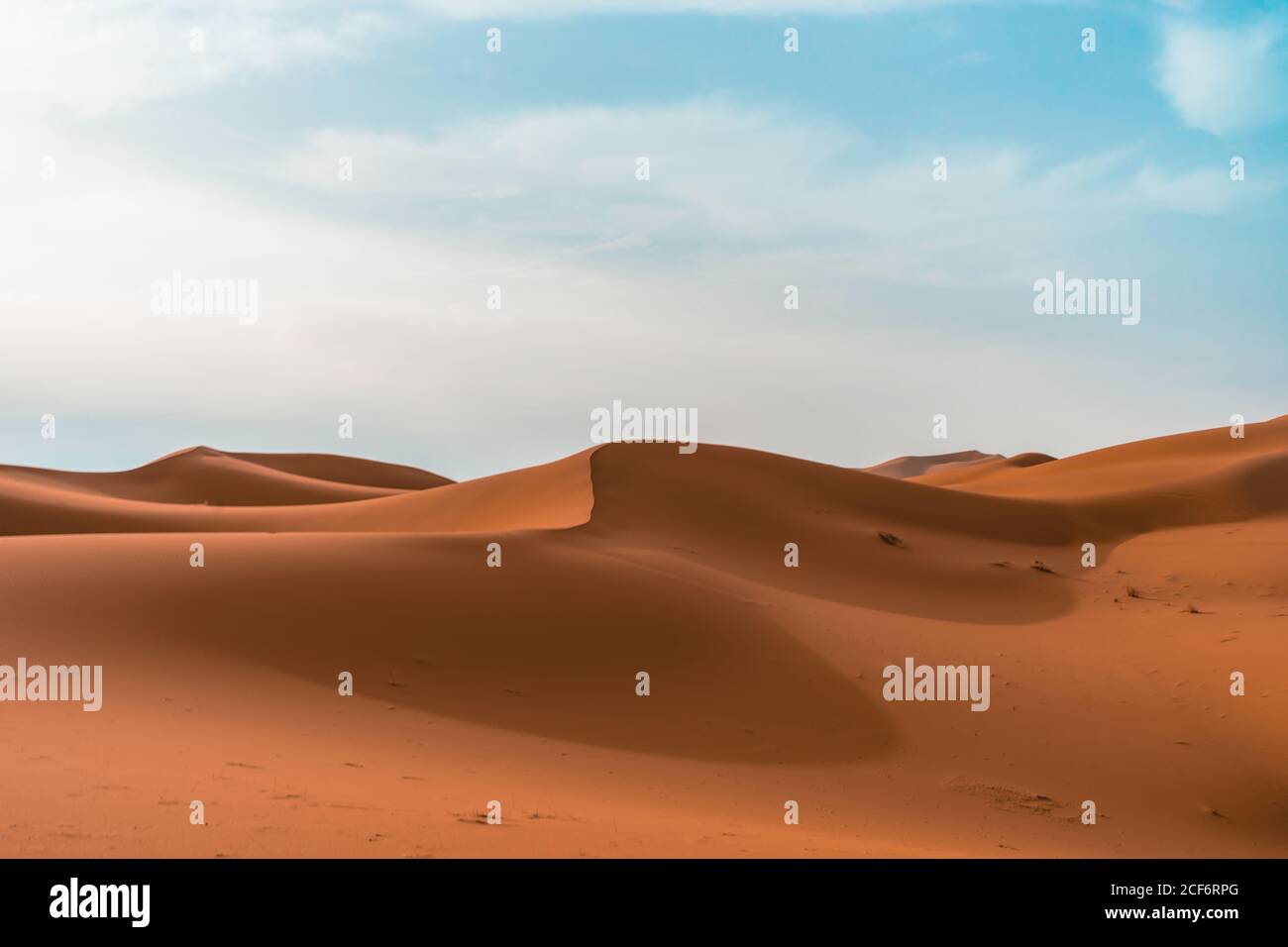 Paysage désertique minimaliste avec dunes de sable sous ciel bleu nuageux par beau temps Banque D'Images