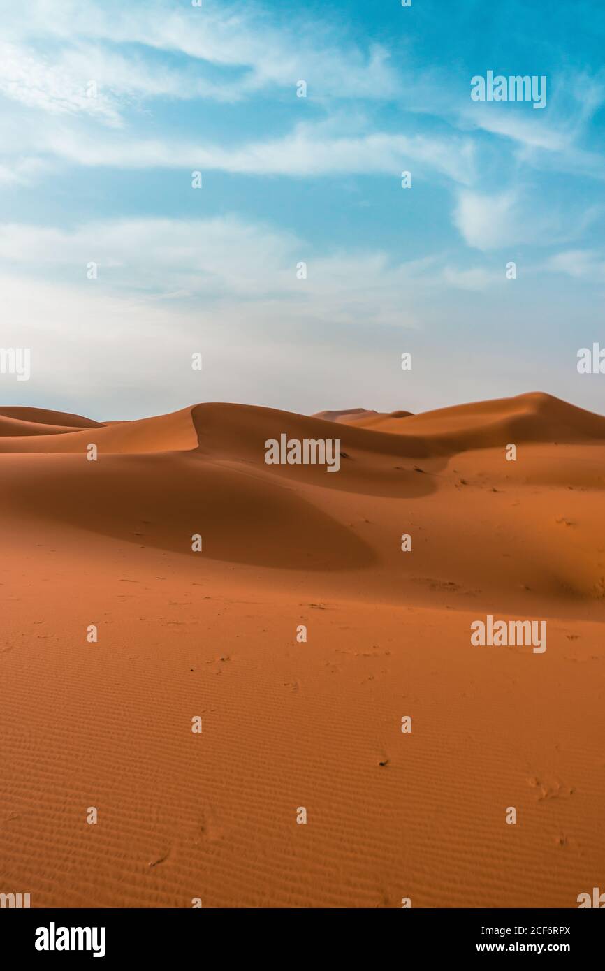 Paysage désertique minimaliste avec dunes de sable sous ciel bleu nuageux par beau temps Banque D'Images