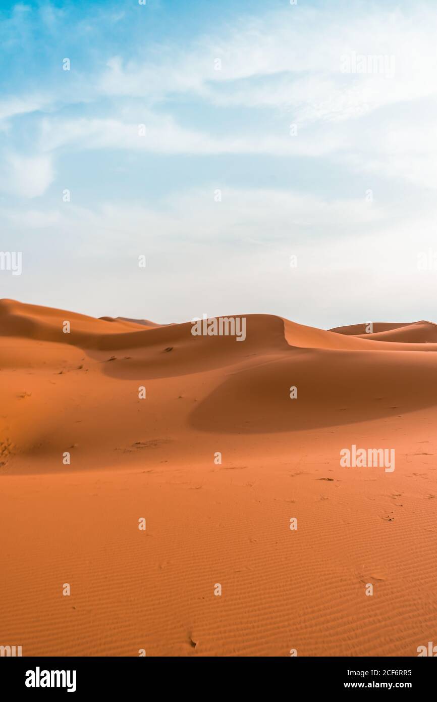 Paysage désertique minimaliste avec dunes de sable sous ciel bleu nuageux par beau temps Banque D'Images