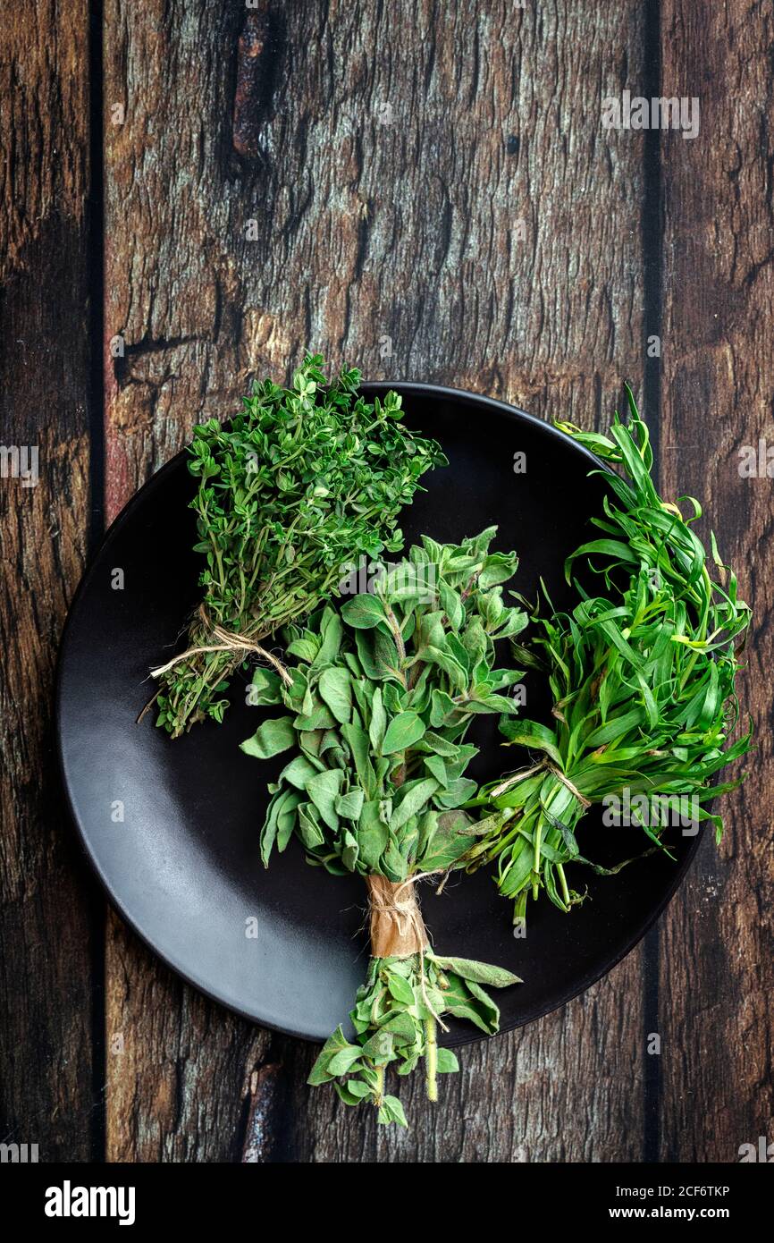 Vue de dessus de la plaque ronde remplie de différents vert frais herbes aromatiques placées sur une table en bois Banque D'Images