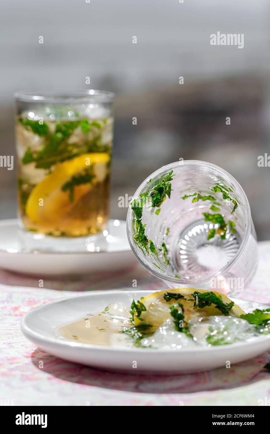 Du thé glacé avec des cubes d'eau congelés a été renversé sur la soucoupe avec du citron et menthe Banque D'Images Du thé glacé avec des cubes d'eau congelés a été renversé sur la soucoupe avec du citron et menthe Banque D'Images