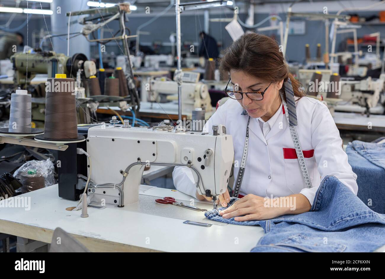 Femme travaillant mains dans une usine de textile couture sur une machine à coudre  industrielle. Production industrielle Photo Stock - Alamy