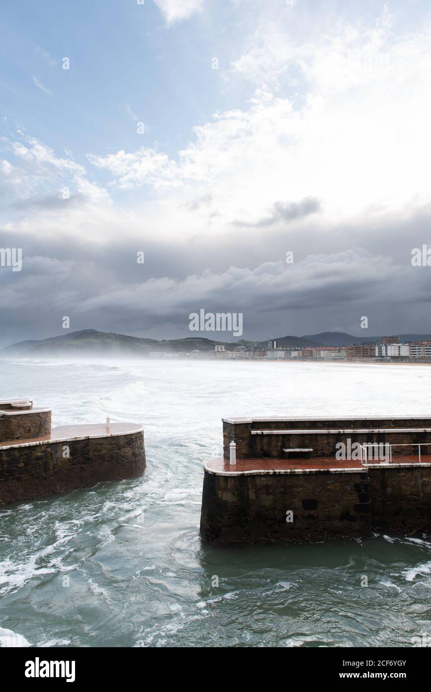 Brise-lames de roche avec la mer qui fait rage par temps nuageux Banque D'Images