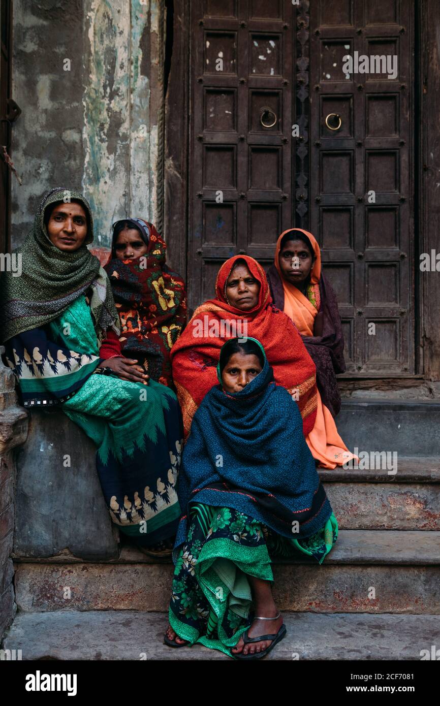 Varanasi, Inde - FÉVRIER, 2018: Groupe de femmes hindoues graves dans des  vêtements traditionnels colorés avec des foulards sur la tête assis ou  debout à côté de la porte de bâtiment fragile