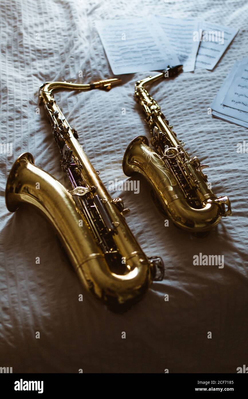 Des saxophones et des feuilles de musique imprimée draps blancs sur le lit Banque D'Images