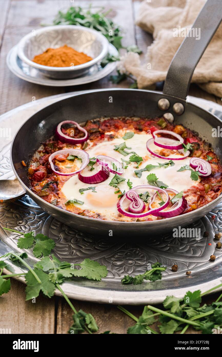 Shakshuka parfumé avec rondelles d'oignon dans une casserole Banque D'Images