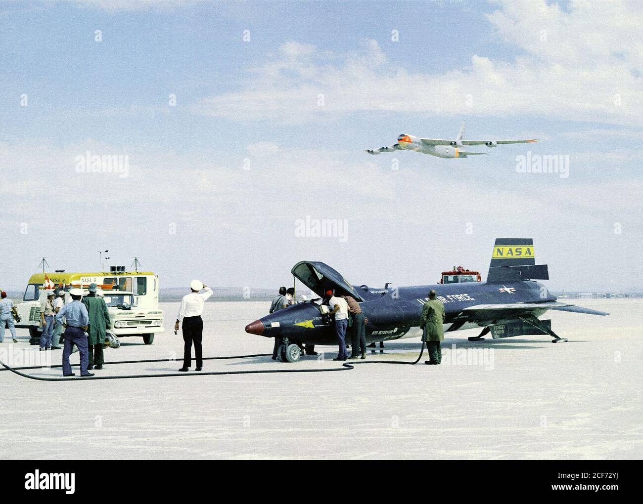 Comme les membres d'équipage sécurisent l'avion X-15 propulsé par une fusée après un vol de recherche, la mère B-52 utilisée pour lancer cet avion unique fait un faible survol. Les X-15 ont effectué un total de 199 vols sur une période de près de 10 ans de 1959 à 1968 et ont établi des records non officiels de vitesse et d'altitude mondiales de 4 520 mph (Mach 6.7) et de 354 200 pieds. L'information obtenue grâce au programme X-15 très fructueux a contribué à l'élaboration des programmes de vol spatial pilotés Mercure, Gemini et Apollo, ainsi qu'au programme de navette spatiale. Banque D'Images