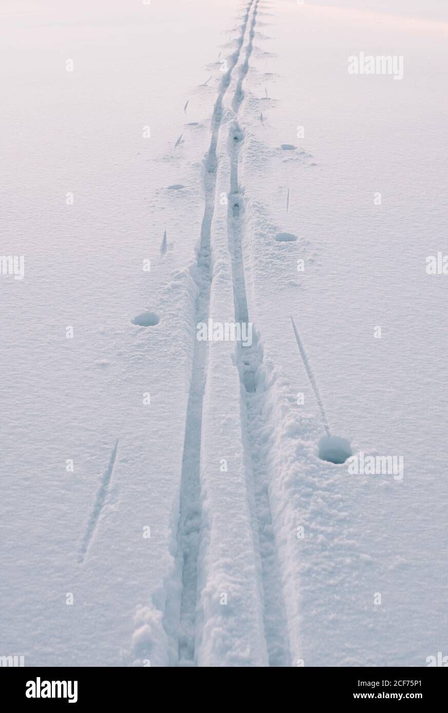 Fond naturel d'hiver avec neige blanche claire et traces de skis et bâtons de ski par temps ensoleillé Banque D'Images