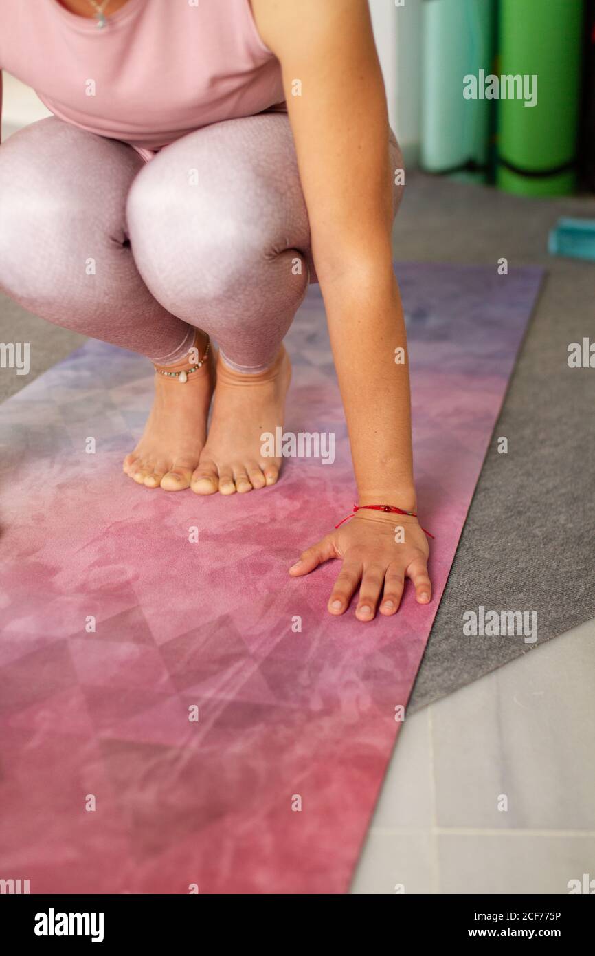 Femme sans visage dans les vêtements de sport faisant l'équilibre simple  position yoga sur le tapis rose en studio Photo Stock - Alamy