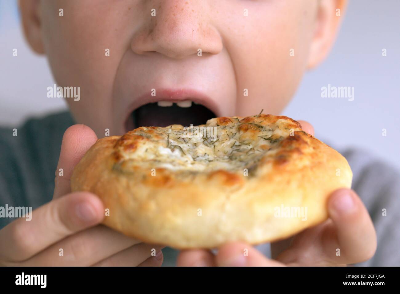 Vue rapprochée d'un garçon mangeant un beignet. Enfant mangeant de la nourriture de restauration rapide malsaine. Le problème est l'obésité infantile Banque D'Images