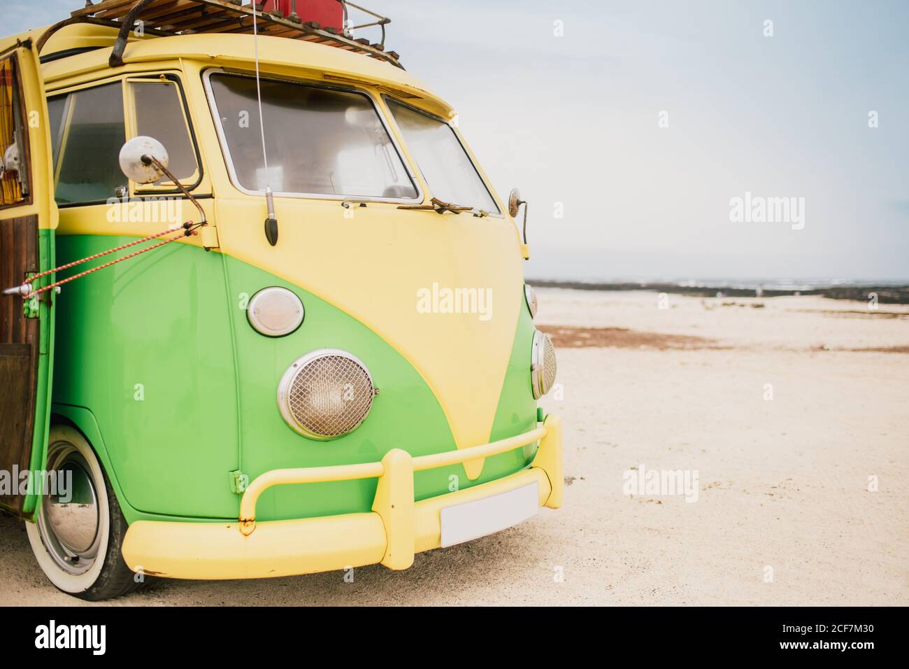 Minibus rétro lumineux avec phares ronds sur la plage Banque D'Images