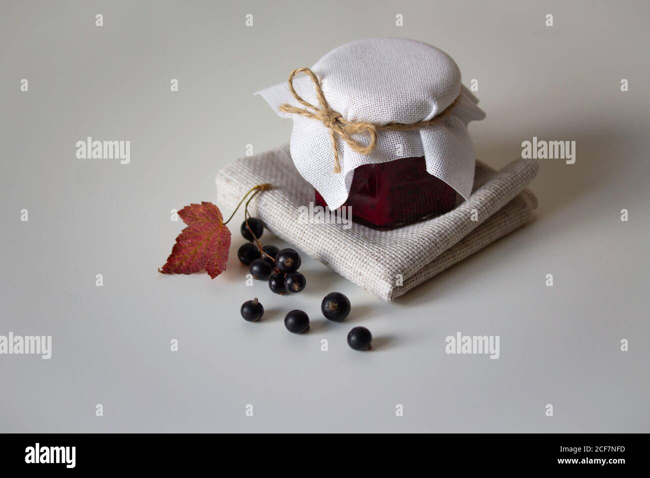 Confiture de cassis dans des pots en verre. Baies fraîches avec feuilles et tiges. Récolte et conserves d'automne. Aliments biologiques. Photographie de la vie Banque D'Images