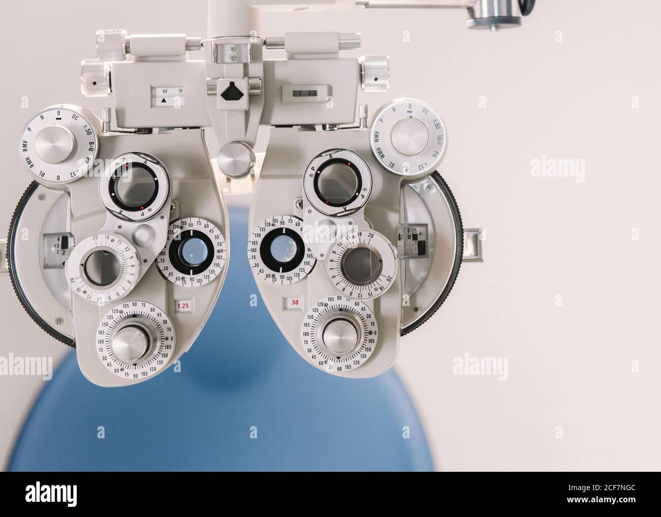 Équipement de test de vision moderne et chaise contre le mur blanc dans cabinet d'opticien en clinique Banque D'Images