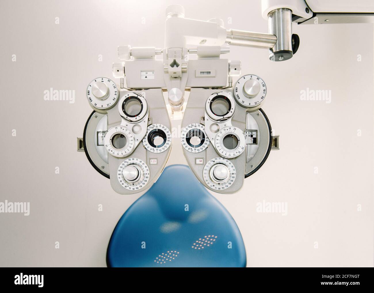 Équipement de test de vision moderne et chaise contre le mur blanc dans cabinet d'opticien en clinique Banque D'Images