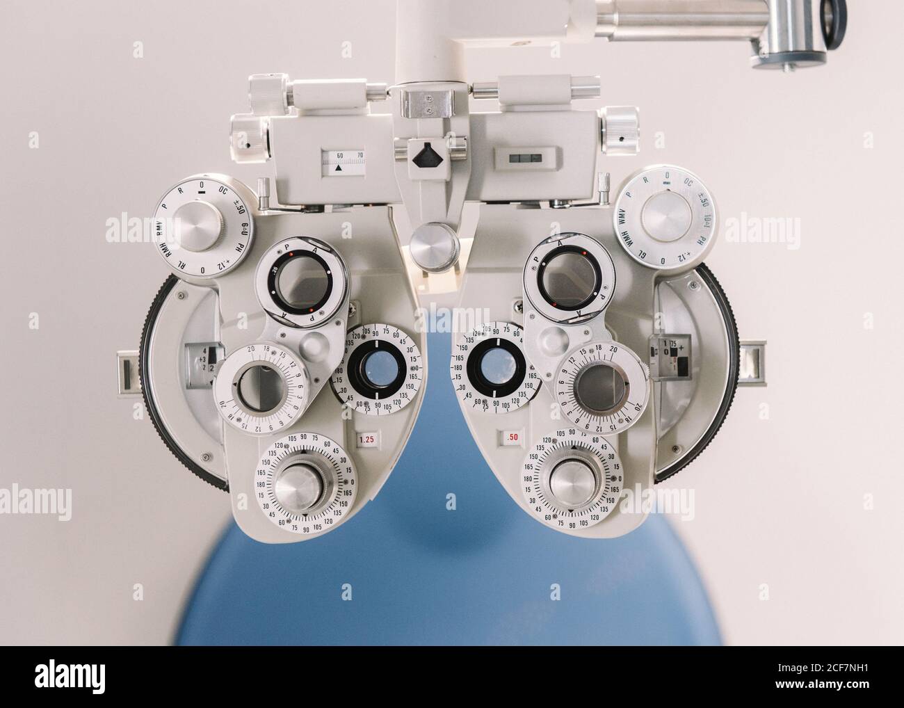 Équipement de test de vision moderne et chaise contre le mur blanc dans cabinet d'opticien en clinique Banque D'Images