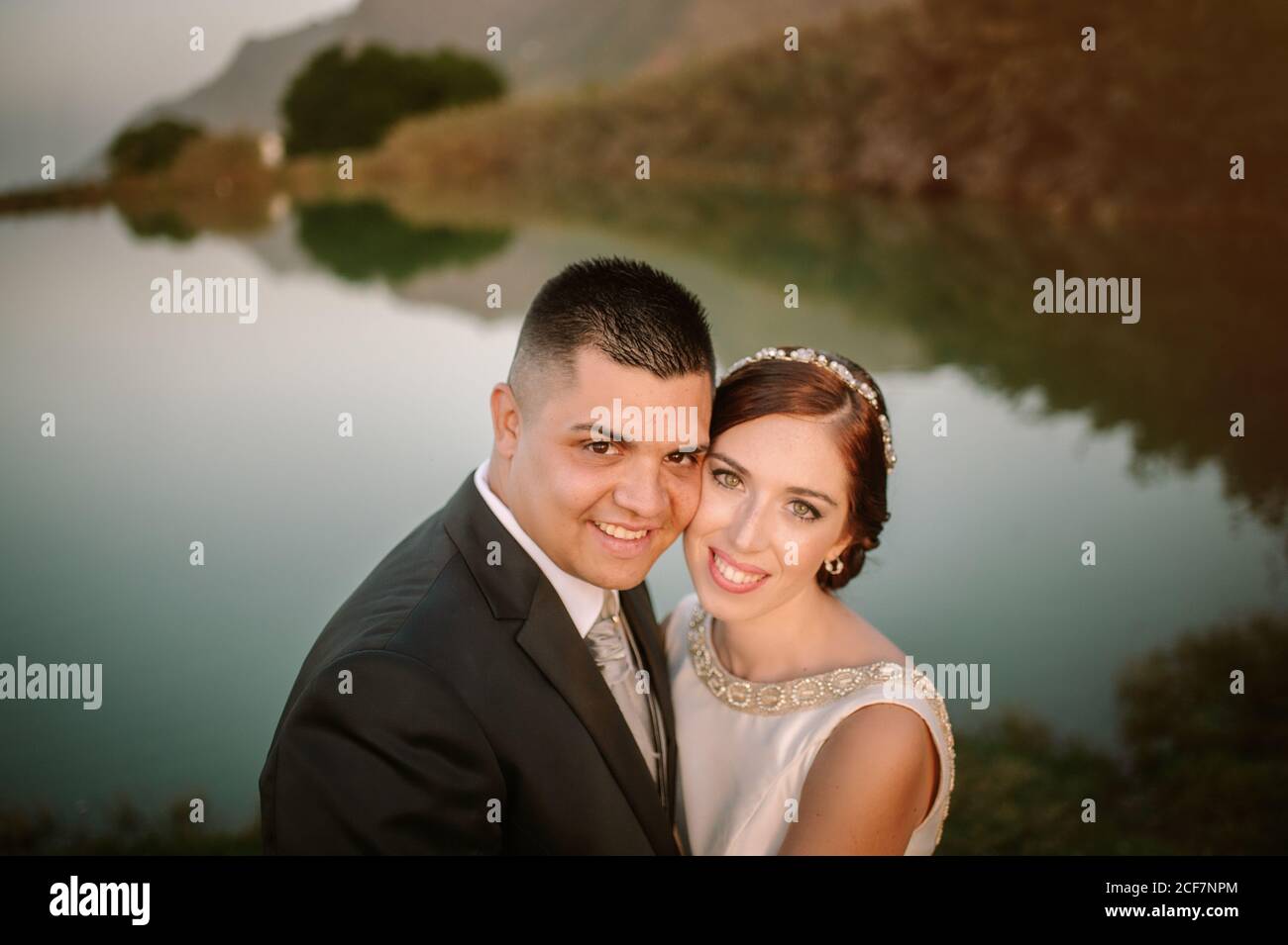 Charmante mariée souriante et salle à manger pleine de charme caméra sur fond de lac de cristal calme entouré de verdure et les collines Banque D'Images