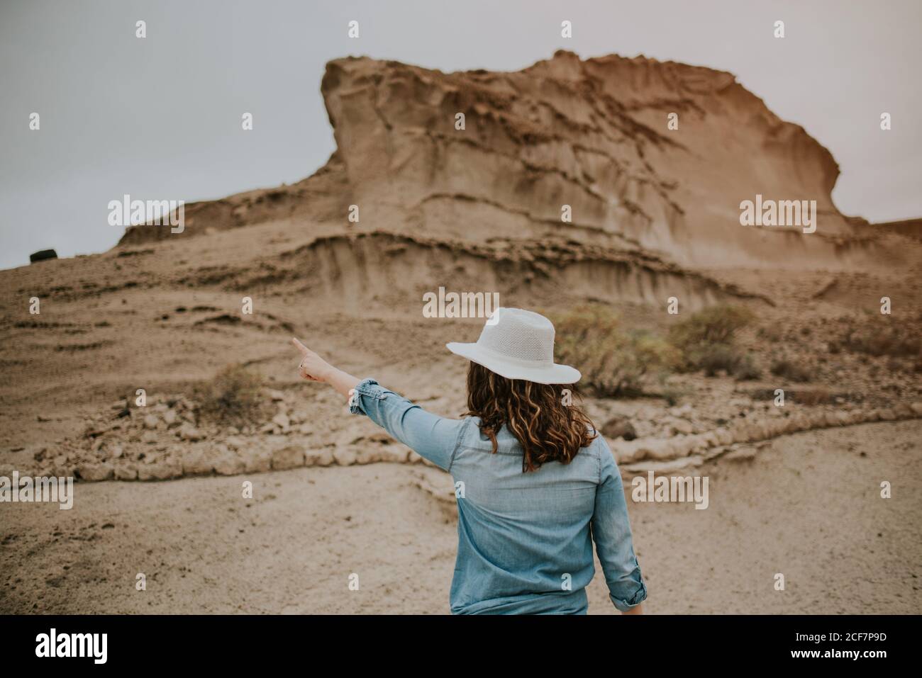 Vue arrière d'une femme méconnaissable vêtue de vêtements décontractés sur les dunes de sable du désert et montrant le jour sombre Banque D'Images