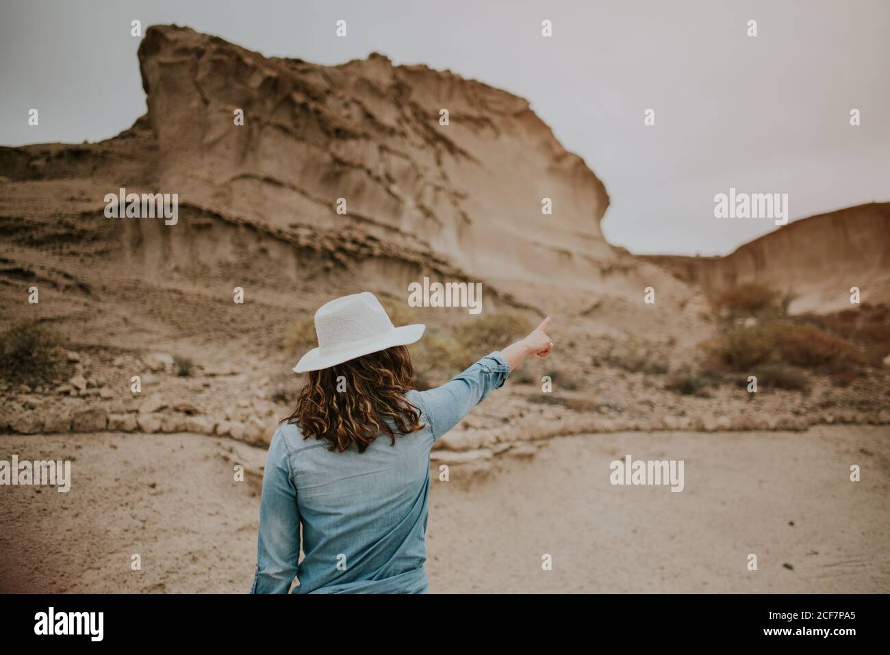 Vue arrière d'une femme méconnaissable vêtue de vêtements décontractés sur les dunes de sable du désert et montrant le jour sombre Banque D'Images