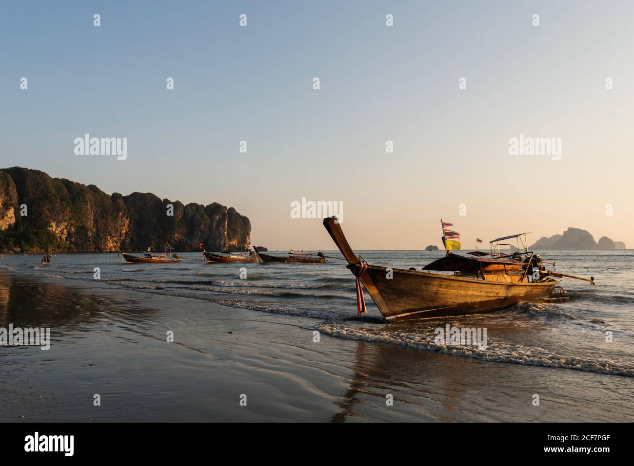 Plage de sable et bateaux sur la mer ondulée pendant le beau coucher du soleil En Thaïlande Banque D'Images