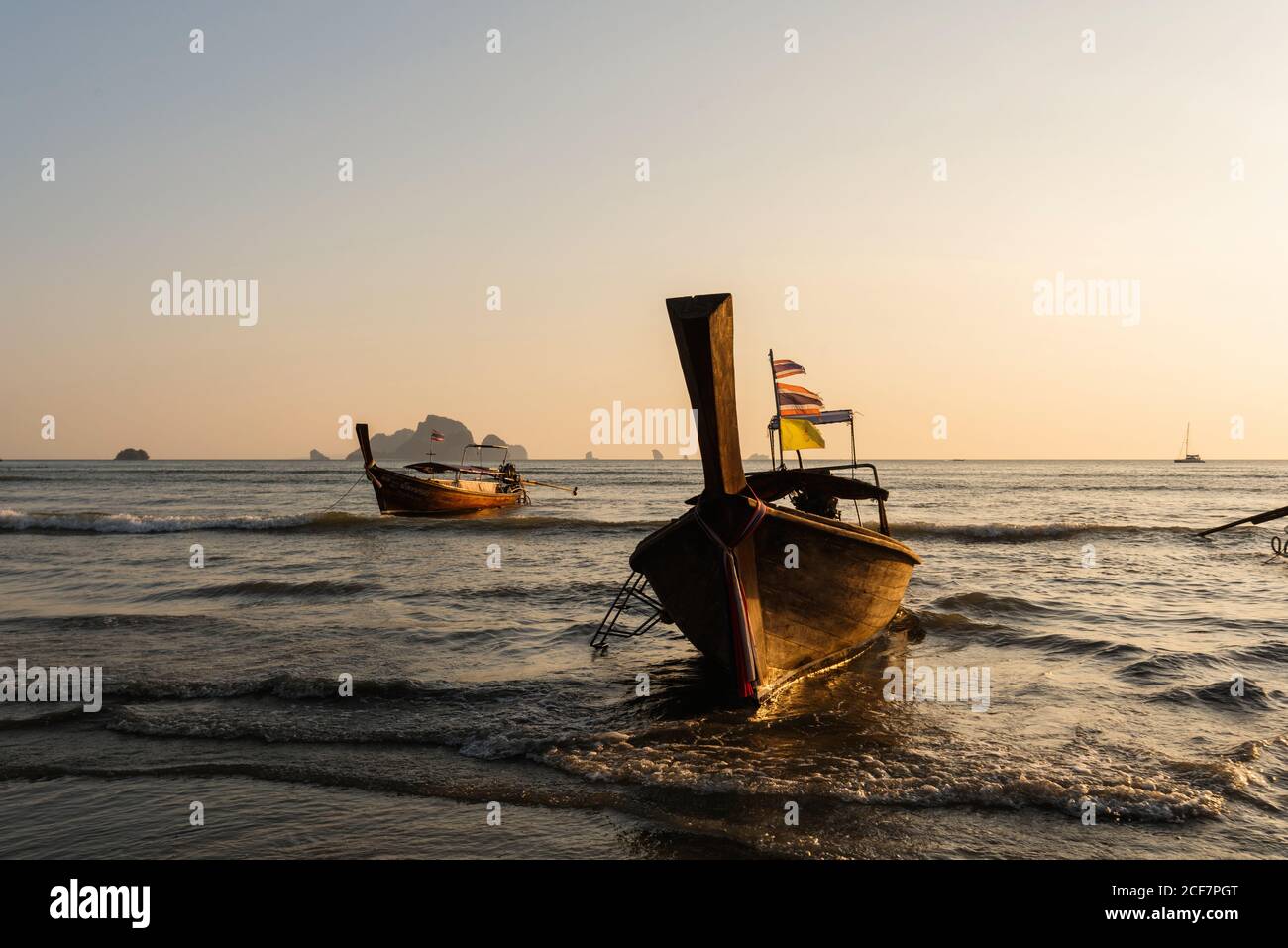 Plage de sable et bateaux sur la mer ondulée pendant le beau coucher du soleil En Thaïlande Banque D'Images