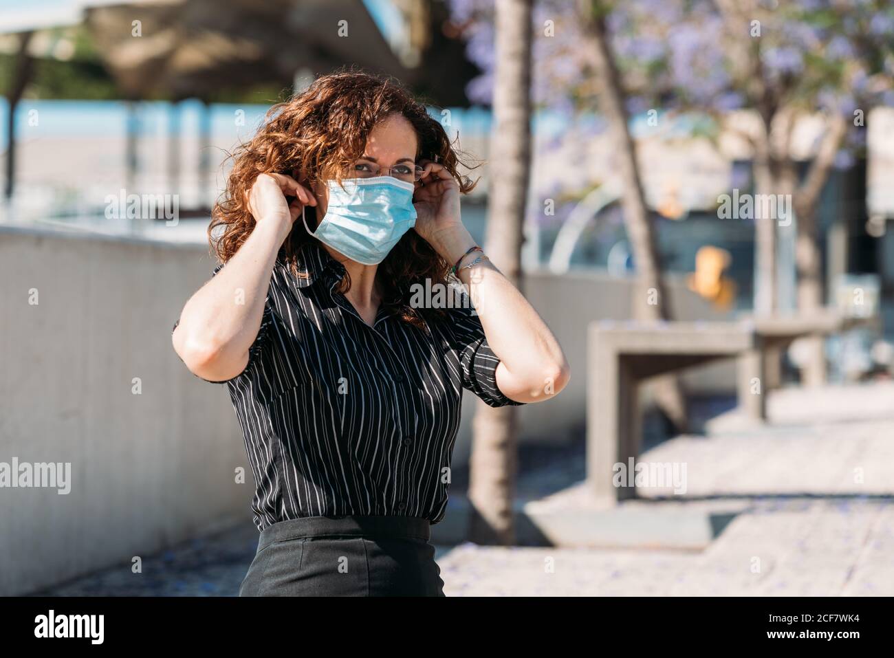 Femme dans la rue qui ajuste son masque lors d'une épidémie virale. Banque D'Images