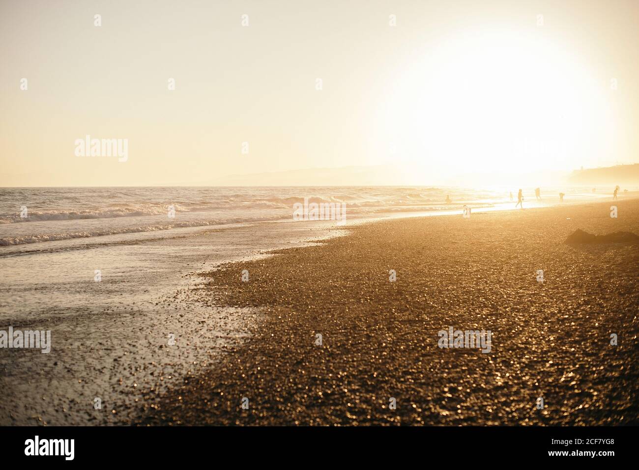 Coucher de soleil vibrant dans un ciel très nuageux sur une plage ondulée tranquille avec plage de sable Banque D'Images