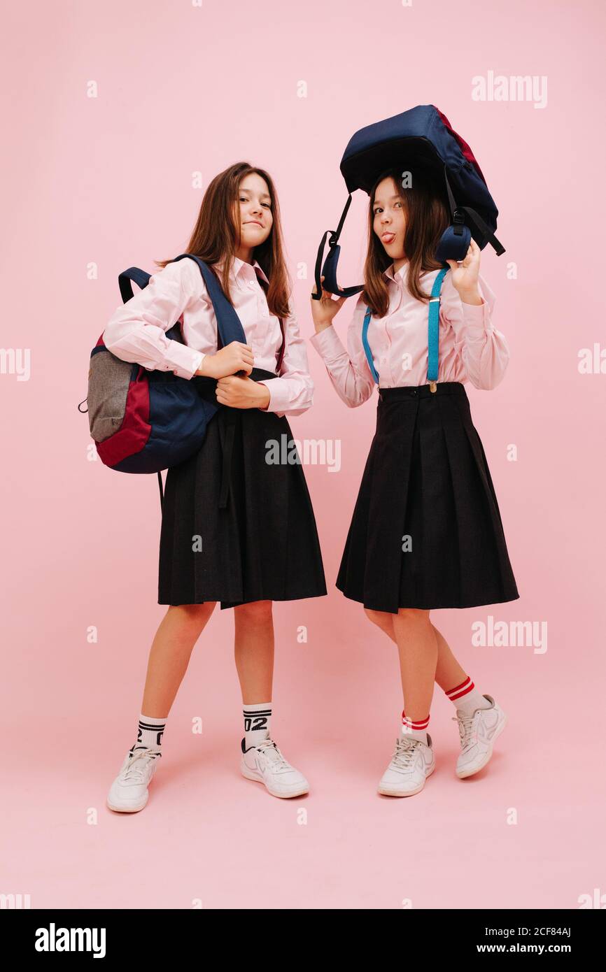 Bonne petite fille jumelle d'école posant avec leurs sacs à dos. Angle bas Banque D'Images