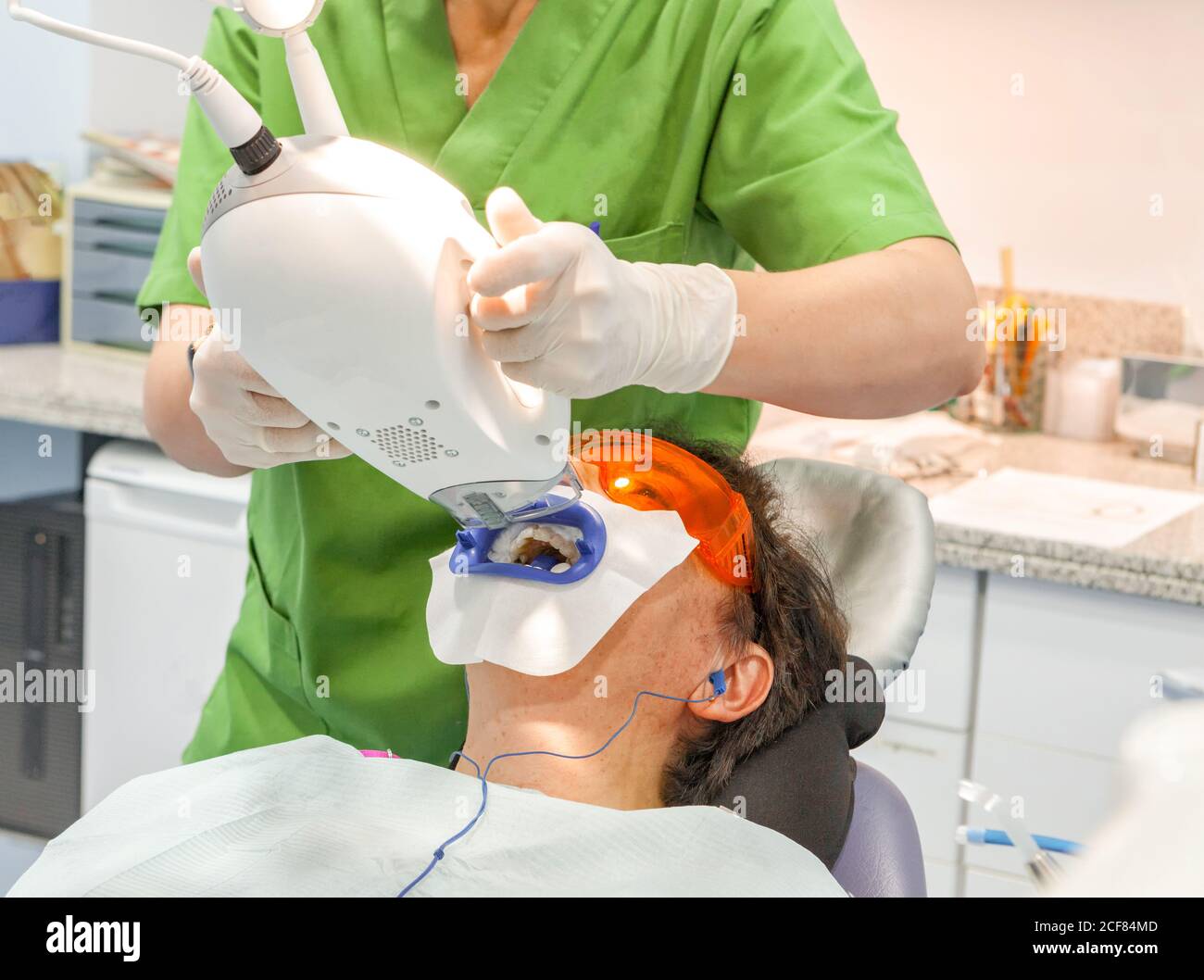 Patient allongé avec une bouche ouverte dans des lunettes de protection rouges pendant spécialiste des cultures prenant des rayons x numériques Banque D'Images