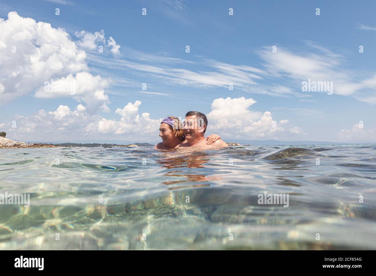 Couple d'hommes et de femmes âgés qui apprécient l'eau douce tout en nageant ensemble dans l'eau cristalline par temps lumineux, Halkidiki, Grèce Banque D'Images