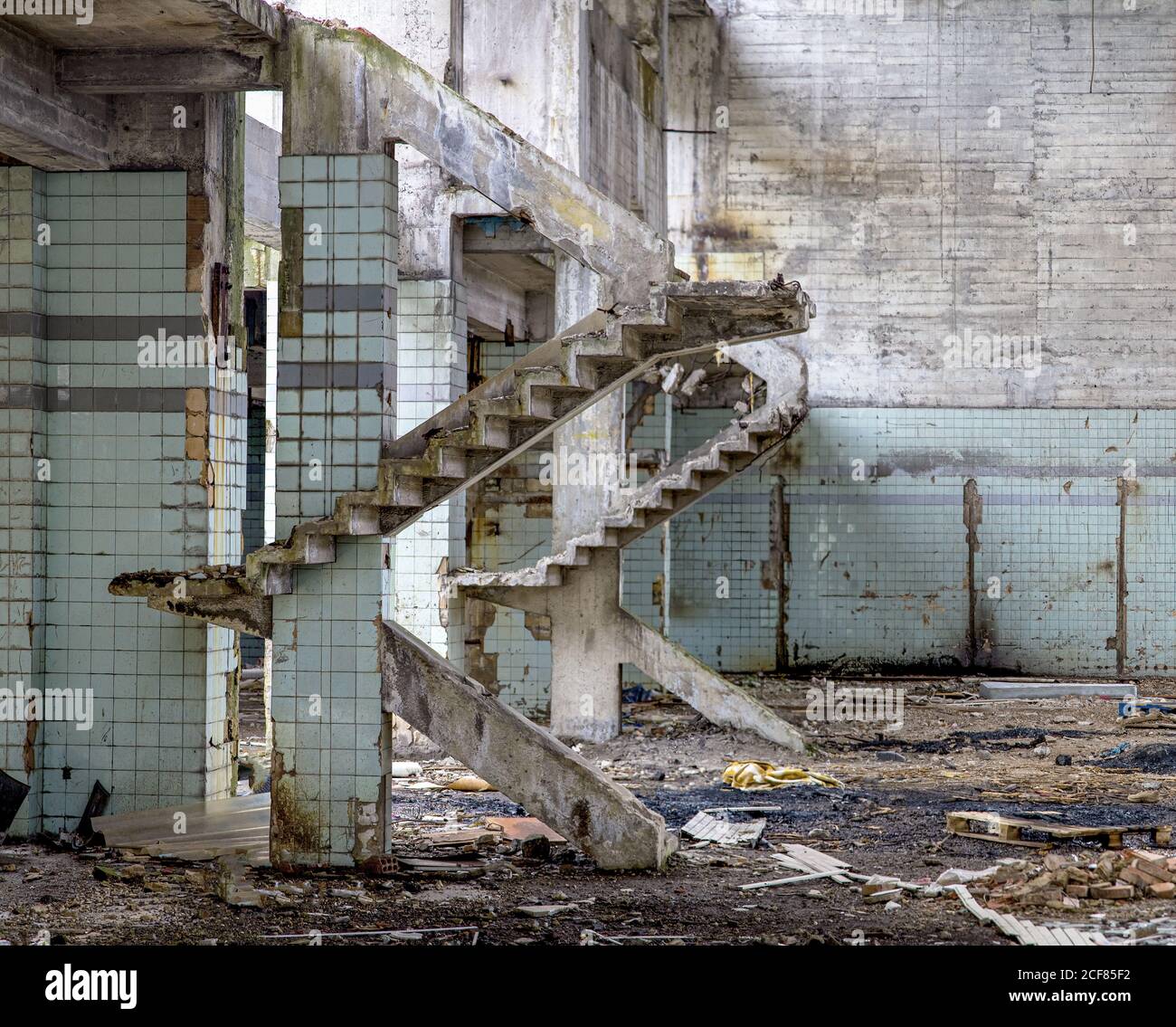 Murs en béton et restes d'escaliers dans l'ancien industriel abandonné bâtiment avec un sol désordonné Banque D'Images