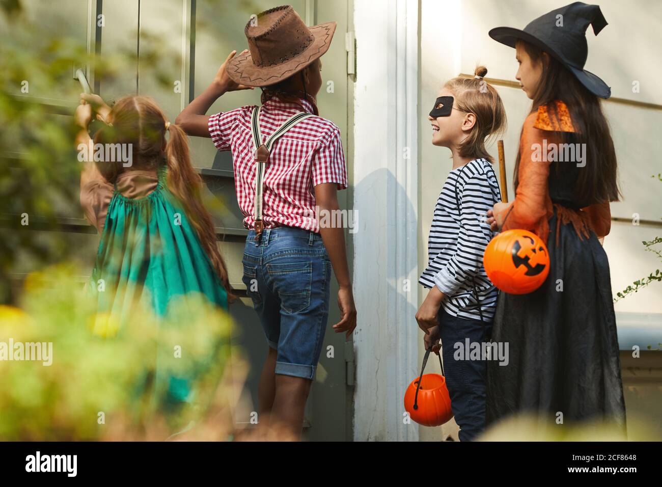 Groupe d'enfants en costumes d'Halloween cognant dans la porte et dites « trick » ou « treat » Banque D'Images