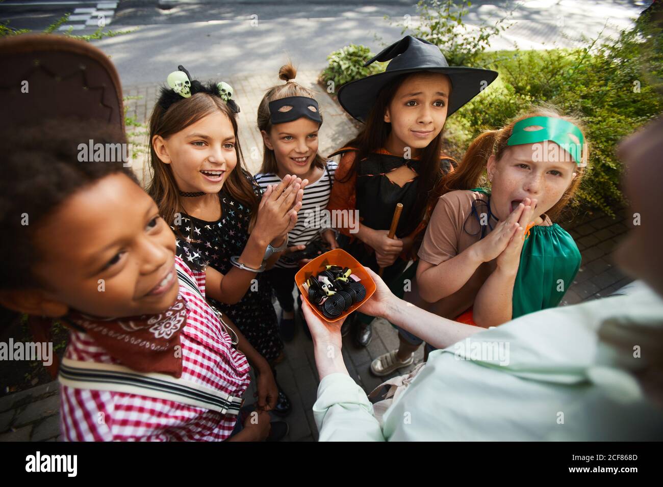 Groupe d'enfants en costumes d'Halloween demandant des bonbons pendant aller à des maisons Banque D'Images