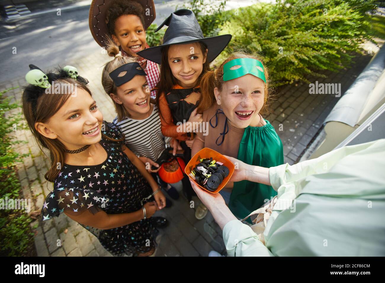 Gros plan sur une femme qui traite des enfants avec des bonbons pendant les vacances d'Halloween à l'extérieur Banque D'Images