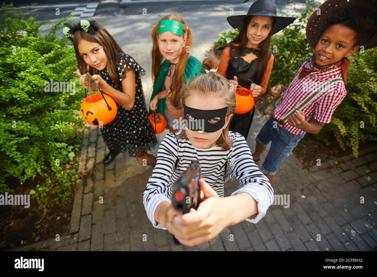 Groupe d'enfants dans les costumes d'Halloween jouant le tour ou le plaisir pendant les vacances, ils se tiennent à l'extérieur et sourient à l'appareil photo Banque D'Images