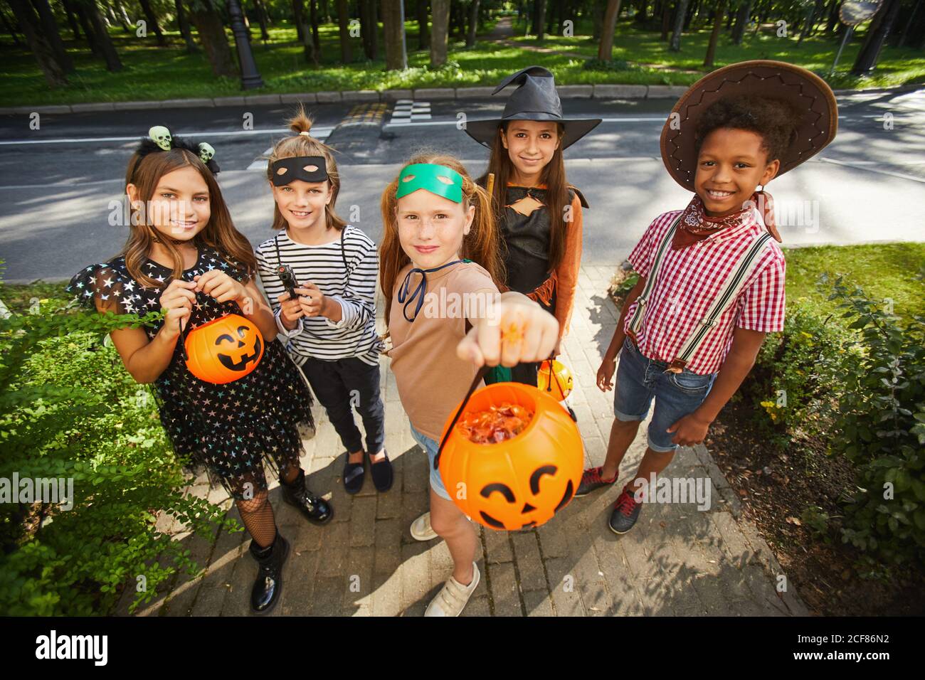 Groupe d'enfants tenant des paniers et demandant des gâteries pendant Halloween vacances plein air Banque D'Images