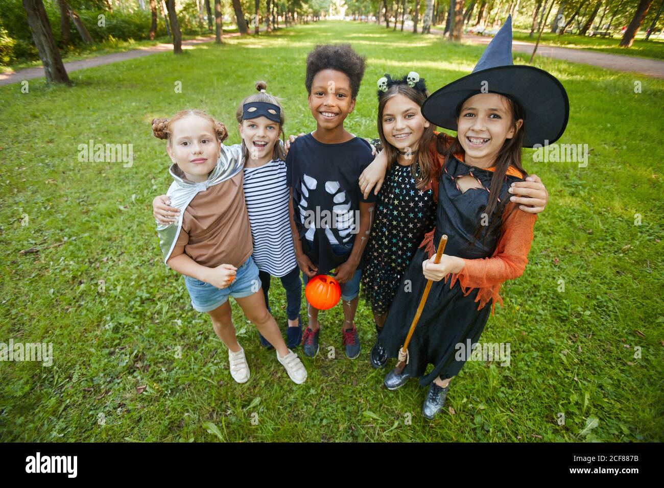 Portrait d'enfants heureux en costumes d'Halloween s'embrassant et sourire à la caméra tout en se tenant dans le parc Banque D'Images